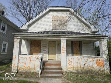 Exterior of boarded up house with graffiti and overgrown landscaping at 124 N Grant Ave, Indianapolis, IN 46201