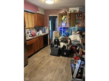 Features a sink, oven, wooden cabinetry, and laminated floors, but is cluttered and in need of decluttering at 3742 S Walcott St, Indianapolis, IN 46227