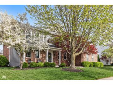 Charming brick home with lush front yard and mature trees offering shade and curb appeal at 8277 Plumwood Ln, Indianapolis, IN 46256