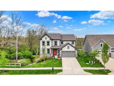 Beautiful two-story home showcases a well-kept lawn and inviting gray facade with a contrasting orange front door at 10294 Pigato Dr, Zionsville, IN 46077