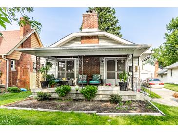 Charming home with an inviting front porch, lovely landscaping, and classic architectural details at 1030 N Butler Ave, Indianapolis, IN 46219