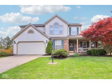 Charming two-story home featuring a well-manicured lawn, attached garage, and inviting front porch with decorative shutters at 11205 Echo Ridge Ln, Indianapolis, IN 46236