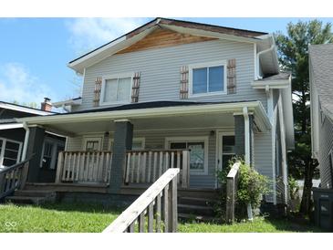 Two-story home with covered porch, wood railings, gray siding, and decorative shutters at 509 N Emerson Ave, Indianapolis, IN 46219
