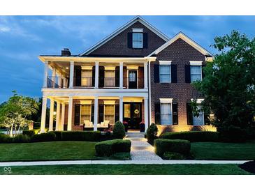 Stunning two-story brick home with a covered front porch, white columns, and manicured lawn at 6655 Westminster Dr, Zionsville, IN 46077