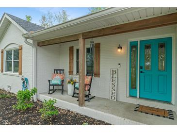 Inviting front porch featuring a vibrant turquoise door, rocking chairs, and natural wood accents at 1285 S 1100 E, Zionsville, IN 46077