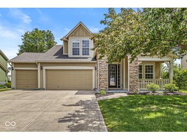 Charming two-story home with stone accents, three-car garage, covered porch, and a well-manicured lawn at 19552 Wagon Trail Dr, Noblesville, IN 46060