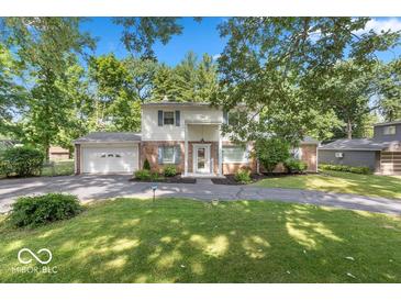 Charming two-story home with a brick facade, attached garage and a beautifully landscaped front yard at 7546 Lindenwood Dr, Indianapolis, IN 46227