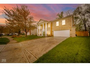 Classic brick home with a grand entrance, columns, and a beautiful landscaped front yard against a colorful sunset at 10090 Eagle Eye Way, Indianapolis, IN 46234