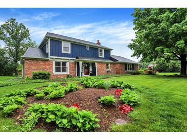 Charming two-story home featuring a brick facade and a well-manicured lawn with lovely flower beds at 1095 Williamsburg Ln, Zionsville, IN 46077