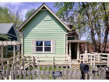 Charming, light green home with a well-maintained yard, quaint fence and accessible ramp at 474 N Randolph St, Indianapolis, IN 46201