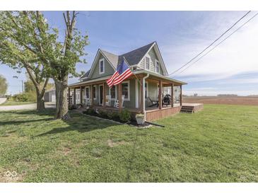 Inviting two-story farmhouse with wraparound porch, rocking chairs, and American flag, set on a large lot at 10776 S 250 W, Flat Rock, IN 47234