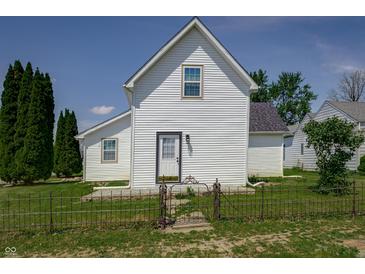 Charming white home featuring black roof, wrought iron fence, manicured lawn, and bright blue sky at 2402 N B St, Elwood, IN 46036