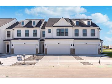 Modern townhome with a white exterior, dark trim, and individual garages with ample parking in the driveway at 3305 Noriker Ln, Zionsville, IN 46077