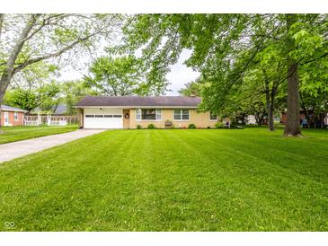 Charming single-story home with lush lawn and an attached garage at 5450 Fenmore Rd, Indianapolis, IN 46228