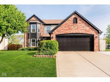 Charming two-story brick home featuring a well-manicured lawn and an attached two-car garage at 6144 Black Oaks Way, Indianapolis, IN 46237