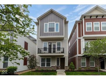 Charming three-story home with a balcony, complemented by manicured landscaping and vibrant greenery at 13323 Susser Way, Fishers, IN 46037