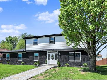 Charming two-story home boasts a striking black brick facade and a welcoming front yard with mature trees at 5354 Brendon Park Dr, Indianapolis, IN 46226