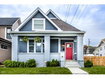 Charming home with a red door, grey painted brick porch, gray siding and well-maintained lawn at 1330 Marlowe Ave, Indianapolis, IN 46202