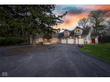 Stunning exterior view of a large home with a three-car garage and a spacious driveway during a vibrant sunset at 15617 Westfield Blvd, Carmel, IN 46033