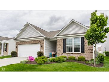Well-maintained exterior with brick accents, a lush green lawn, and mature tree at 16044 Loire Valley Dr, Fishers, IN 46037