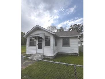Charming home with white siding, front porch, green lawn, and chain link fence at 2414 S Rybolt Ave, Indianapolis, IN 46241