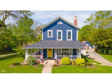 Charming two-story home with a welcoming front porch, yellow door, and beautifully landscaped front yard at 3405 W 8Th Street Rd, Anderson, IN 46011