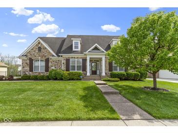 Charming stone home featuring a manicured lawn, lush landscaping, and inviting front entrance at 3965 Andretti Dr, Zionsville, IN 46077