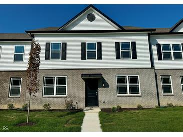 Charming townhome with a gray brick facade and white vinyl siding under a clear blue sky at 6216 Cascades Dr, Whitestown, IN 46075