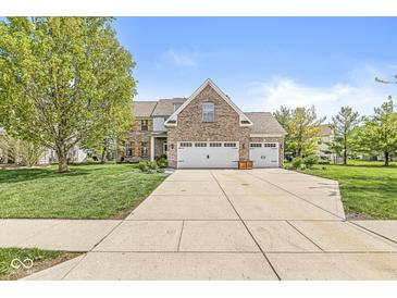 Charming brick home featuring a well-manicured lawn, mature trees, and an attached two-car garage at 6758 Woodcliff Cir, Zionsville, IN 46077