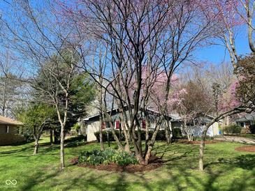Landscaped front yard with flowering trees and vibrant spring flowers at 8728 Holliday Dr, Indianapolis, IN 46260