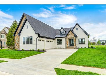 Beautiful home exterior with stone accents, three-car garage, and manicured lawn on a sunny day at 16457 Gleneagles Ct, Noblesville, IN 46060