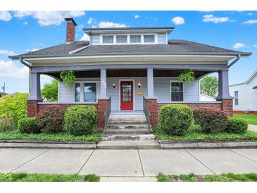 Charming two-story home featuring a covered front porch, red front door, and well-maintained landscaping at 301 Colescott St, Shelbyville, IN 46176