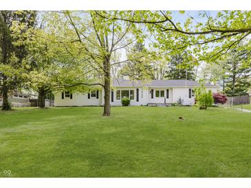 Charming, bright white home with well-maintained lawn, beautiful landscaping, and mature trees at 7950 Westfield Blvd, Indianapolis, IN 46240
