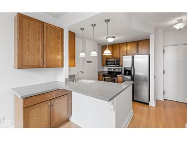 Kitchen with wood cabinets, white countertops, stainless steel appliances, and hardwood floors at 920 E 62Nd St # Apt M7, Indianapolis, IN 46220