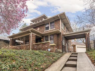 Charming two-story brick home featuring an attached covered area and landscaped front yard at 5181 E Pleasant Run Pkwy S Dr, Indianapolis, IN 46219