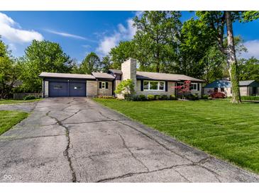 Charming single-story home with stone accents, a well-manicured lawn, and an attached two car garage at 845 W 77Th St S Dr, Indianapolis, IN 46260