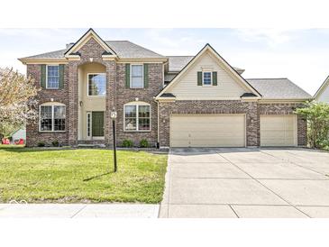 Two-story brick home featuring a three-car garage, well-manicured lawn, and traditional architectural details at 9037 Carnation Dr, Noblesville, IN 46060