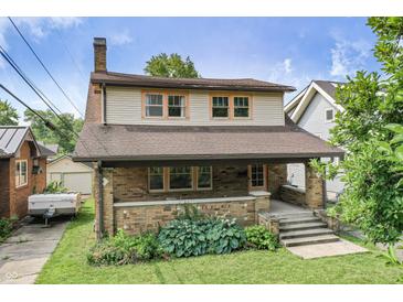 Charming two-story home featuring a brick facade and a welcoming covered front porch at 6051 Lowell Ave, Indianapolis, IN 46219