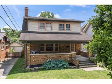 Charming two-story brick home with a welcoming front porch and landscaped front yard at 6051 Lowell Ave, Indianapolis, IN 46219
