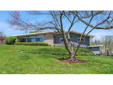Well-maintained home featuring a gray facade, stone accents, and a beautifully landscaped front yard with mature trees at 7310 W 100 N, Greenfield, IN 46140