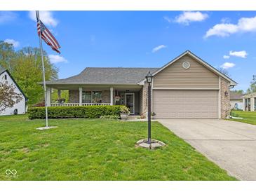 Charming single-story home with a well-manicured lawn, covered porch, and two-car garage on a sunny day at 8451 Sunningdale Blvd, Indianapolis, IN 46234