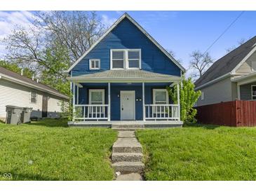 Charming blue two-story home featuring a cozy front porch and landscaped front yard on a sunny day at 1130 W Congress Ave, Indianapolis, IN 46208