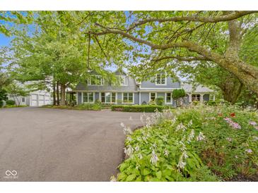Charming gray two-story home with landscaped front yard and attached garage and surrounded by mature trees at 14655 Little Eagle Creek Ave, Zionsville, IN 46077
