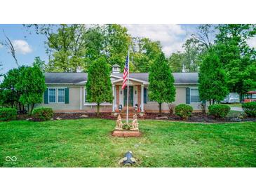 Charming ranch-style home with a lush green lawn, mature trees, and an American flag displayed in the front yard at 5750 W 650 N, Thorntown, IN 46071