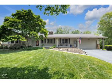 Charming single-story home with a lush green lawn, mature tree, and inviting covered front porch at 7135 Lantern Rd, Indianapolis, IN 46256
