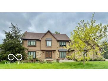 Charming two-story home featuring stone and wood accents, complemented by mature trees and a well-manicured lawn at 1421 Stoney Creek Cir, Carmel, IN 46032