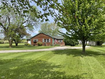 Charming single-story home with green lawn, mature trees, and driveway leading to the attached garage at 1598 Commerce Way, Pittsboro, IN 46167