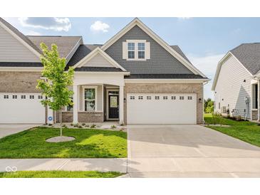 Beautiful two-story home featuring a manicured lawn, charming brick facade, and attached two-car garage at 17023 Adler Ln, Noblesville, IN 46060