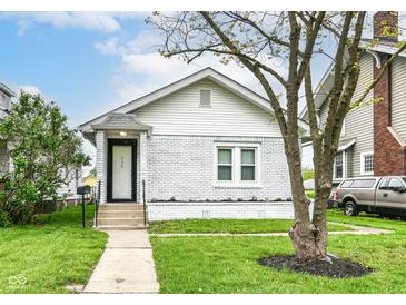 Charming home featuring a white-painted brick exterior, well-manicured lawn, and sidewalk leading to the front door at 736 N Dequincy St, Indianapolis, IN 46201