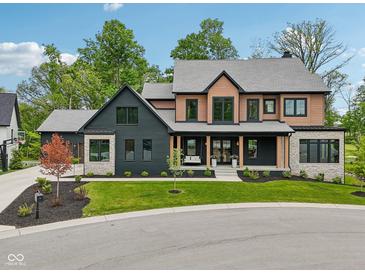 Stunning two-story home featuring a manicured lawn, stylish porch, and a mix of modern black and natural wood accents at 11064 Hamilton Run, Zionsville, IN 46077